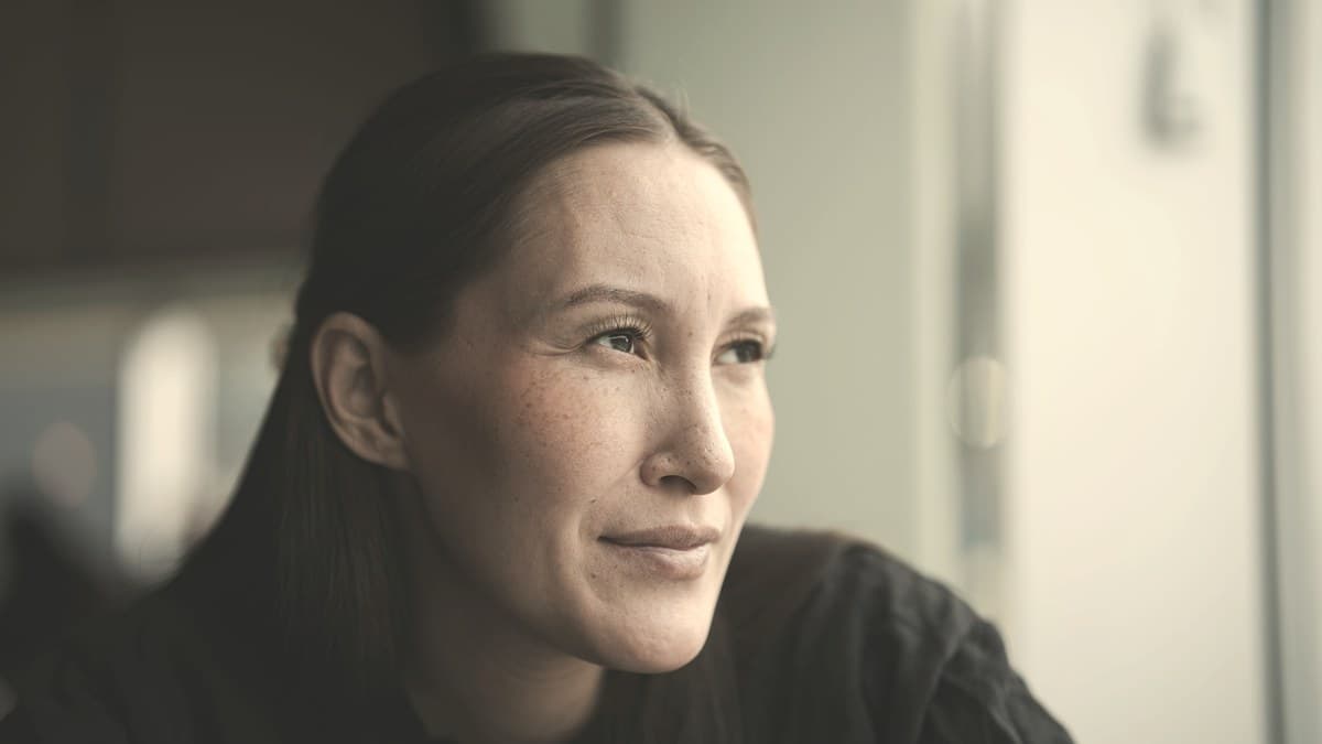 A woman in soft natural window light, reflecting the quiet safety considerations around skinny shots for healthy adults