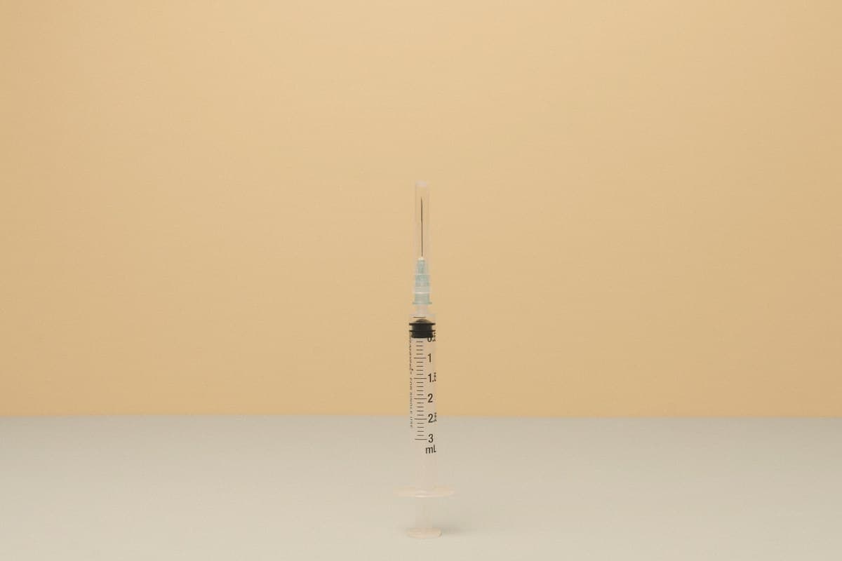 A single medical syringe resting on a clean white surface in soft natural light, illustrating the difference between lipotropic and GLP-1 injection types.