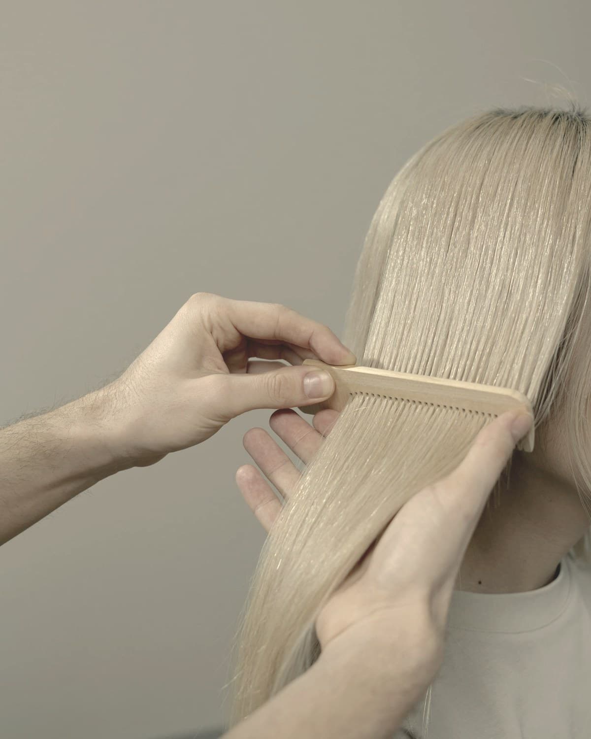 Hands combing long hair with a wooden comb — telogen effluvium causes diffuse shedding three to six months after rapid weight loss begins
