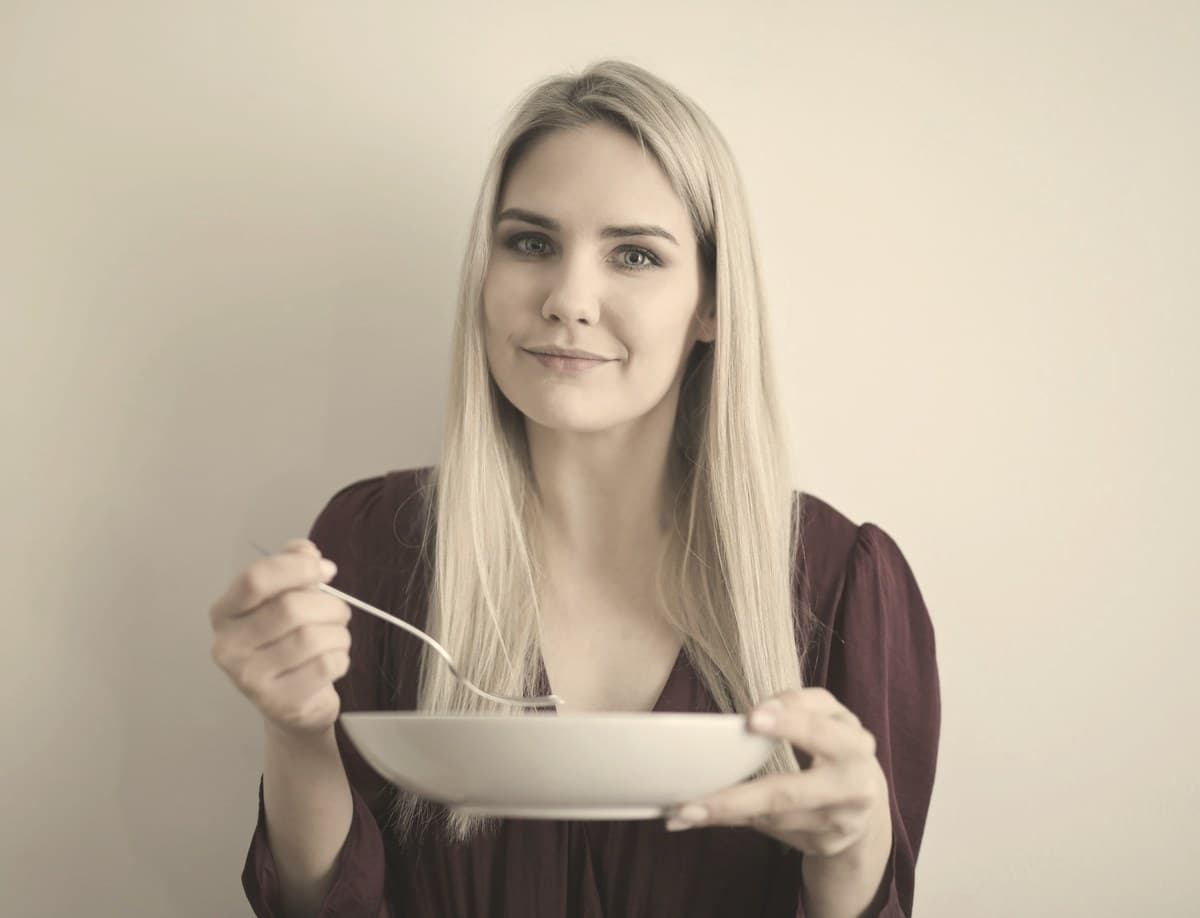 A woman eating a simple, protein-focused meal at a plain table, illustrating mindful eating habits to support GLP-1 weight loss.