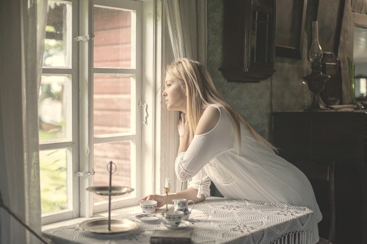 A calm woman gazing out a softly lit window, reflecting on slow and steady progress during GLP-1 treatment over many months.
