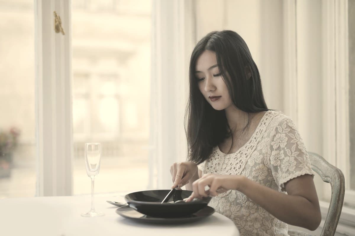 A woman eating a quiet meal by a window, illustrating how gut hormones like GIP and GLP-1 are released after eating to regulate insulin and fullness.