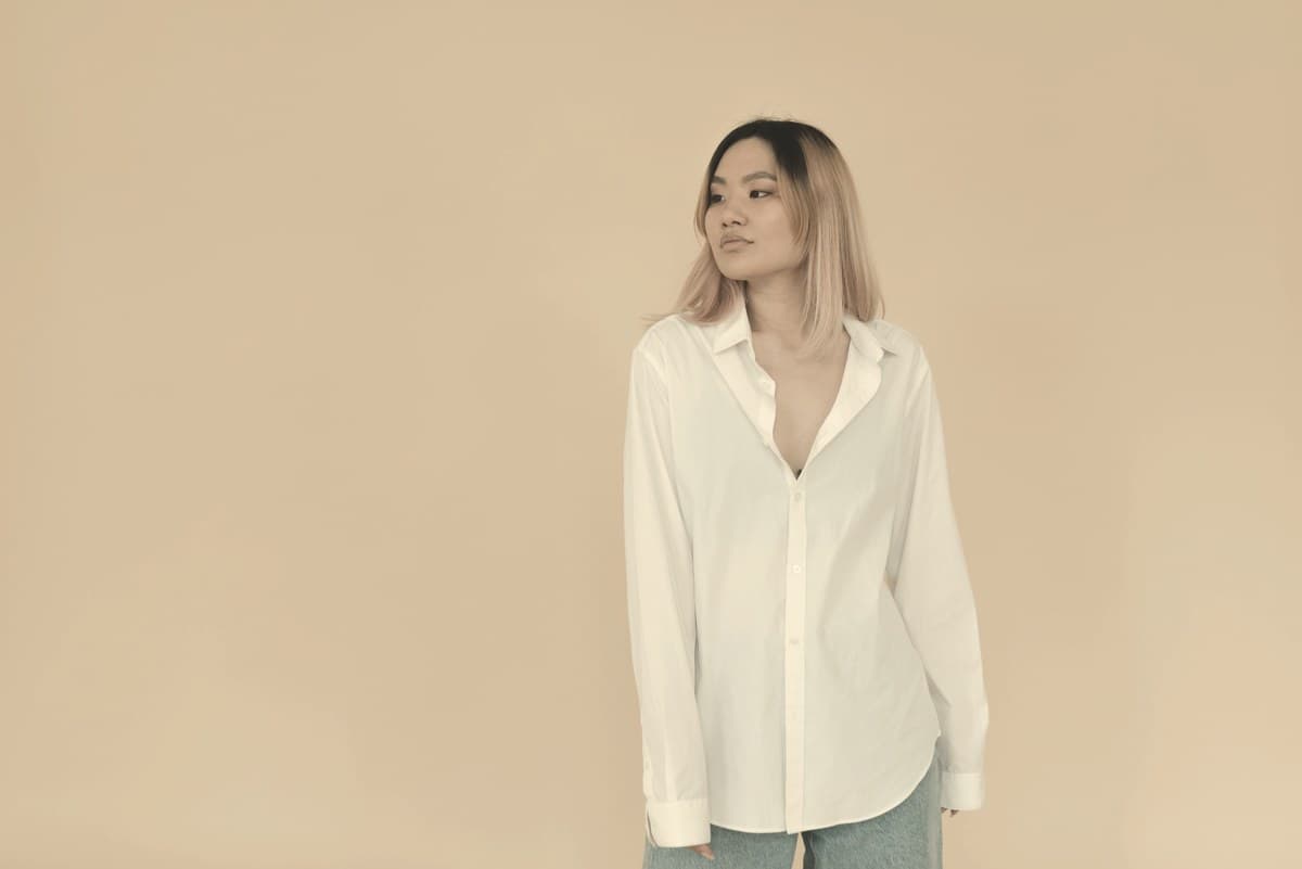 A woman standing quietly against a plain neutral background in soft daylight, representing the chronic weight management outcomes measured in the SURMOUNT-1 trial.