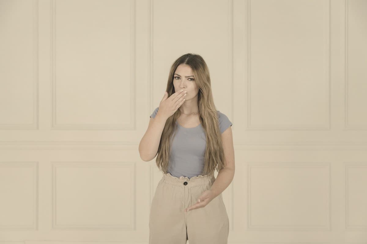 A calm woman resting her hand on her stomach against a soft neutral background, reflecting the nausea side effects discussed in Mounjaro's dose-by-dose data.