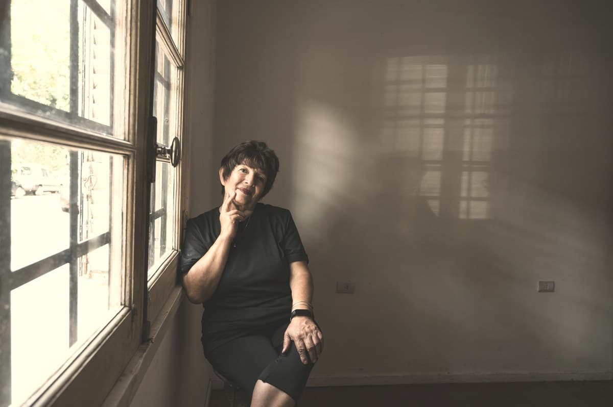 A woman seated thoughtfully near a window against a neutral wall, representing the careful personal decision-making involved in comparing injectable versus oral GLP-1 options.