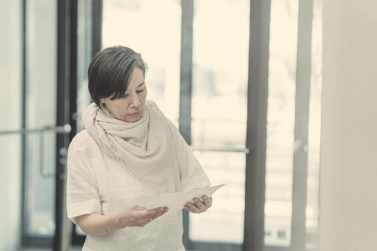 A person quietly reviewing printed documents against a plain background, echoing the section on real scientific research into oral tirzepatide formulations.