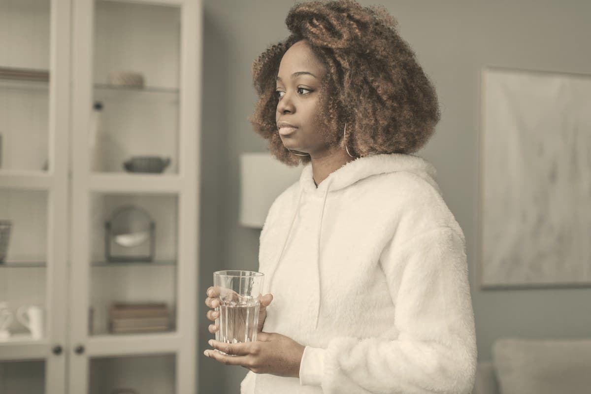 A calm woman drinking a small glass of water in soft morning light, reflecting the Ozempic pill's empty-stomach morning dosing rule