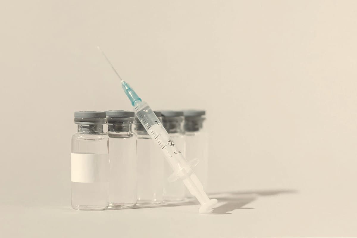 Row of clear injectable medication vials with a syringe on a white background — retatrutide is an investigational once-weekly subcutaneous injection not yet sold in pharmacies