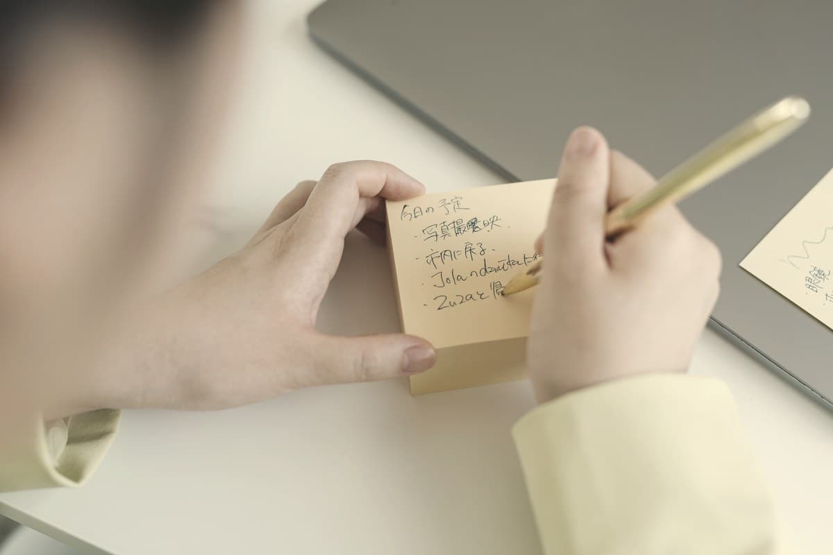 A hand writing a simple note on paper against a plain background, illustrating an easy low-tech method for tracking weekly Ozempic injection site rotation.