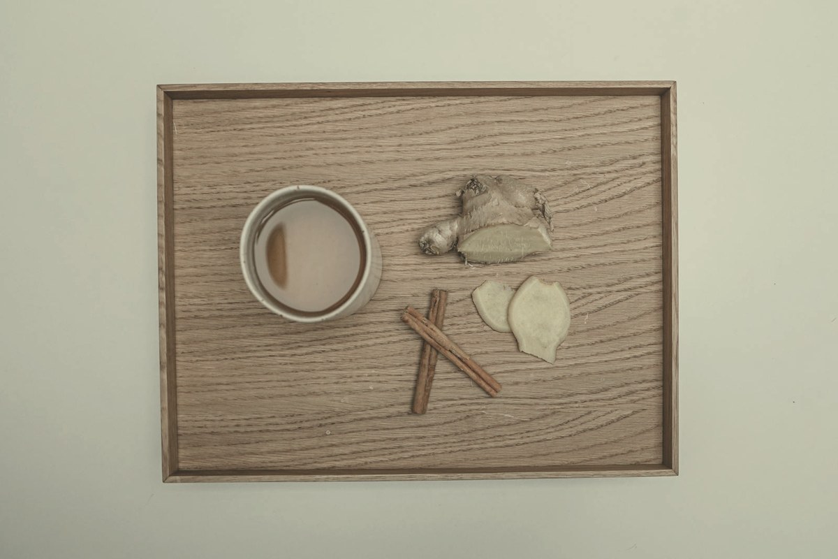 Cup of ginger tea with fresh ginger root and cinnamon on a wooden tray — ginger and small low-fat meals are among the most effective ways to reduce GLP-1 nausea