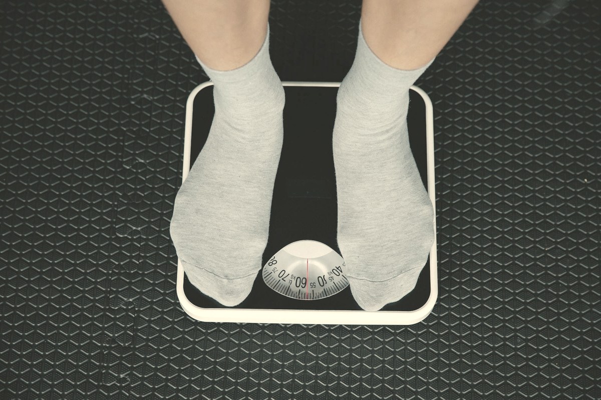 Person's feet on a bathroom scale — stopping a GLP-1 typically brings back most of the lost weight within a year as appetite biology returns