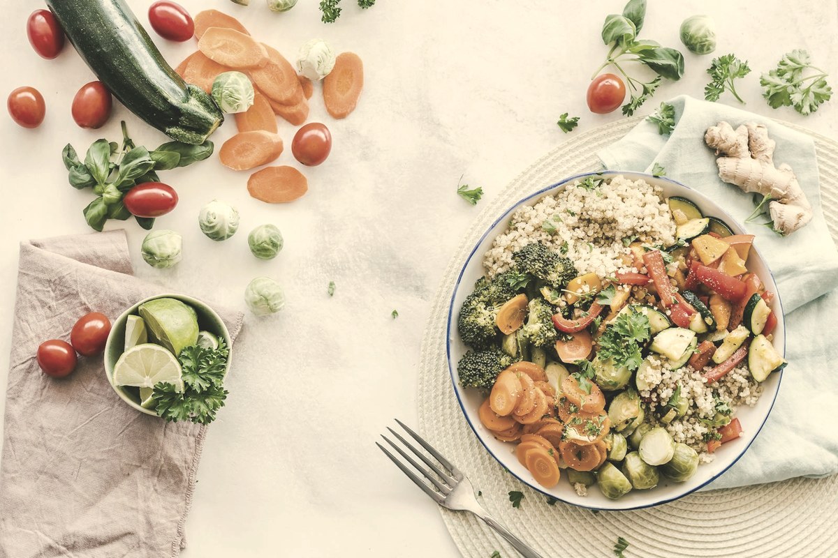 Bowl of roasted vegetables and quinoa surrounded by fresh produce — using GLP-1 appetite suppression to eat smaller, protein-forward meals drives faster weight loss