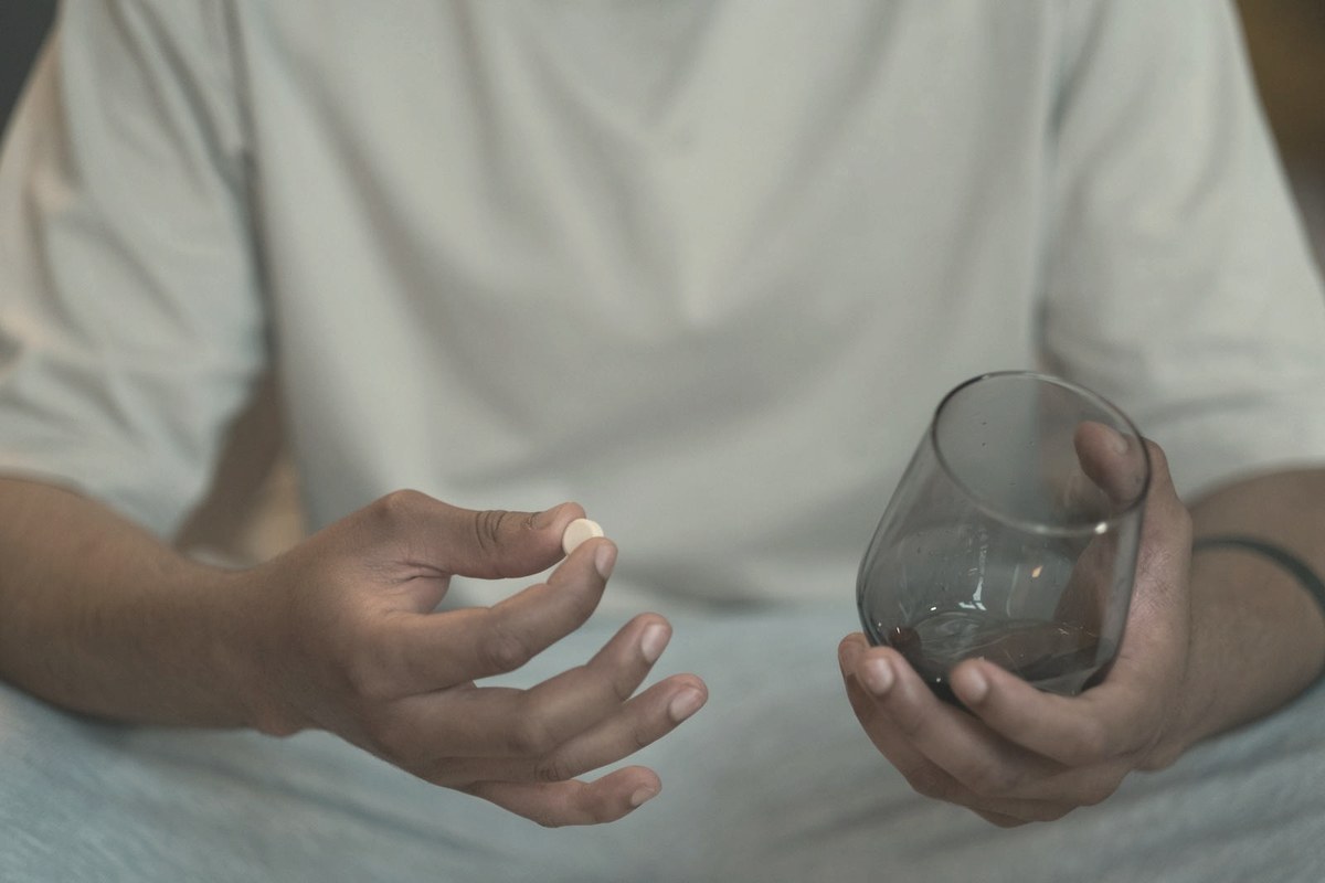 Man taking a daily oral tablet with a glass of water — once-daily oral GLP-1s like orforglipron may improve long-term adherence for needle-averse patients