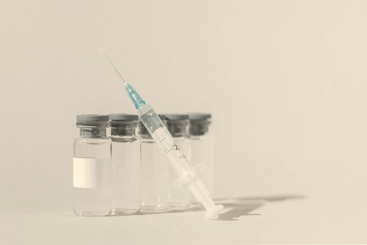 Row of clear injectable medication vials with a syringe on a white background — retatrutide is an investigational once-weekly subcutaneous injection not yet sold in pharmacies