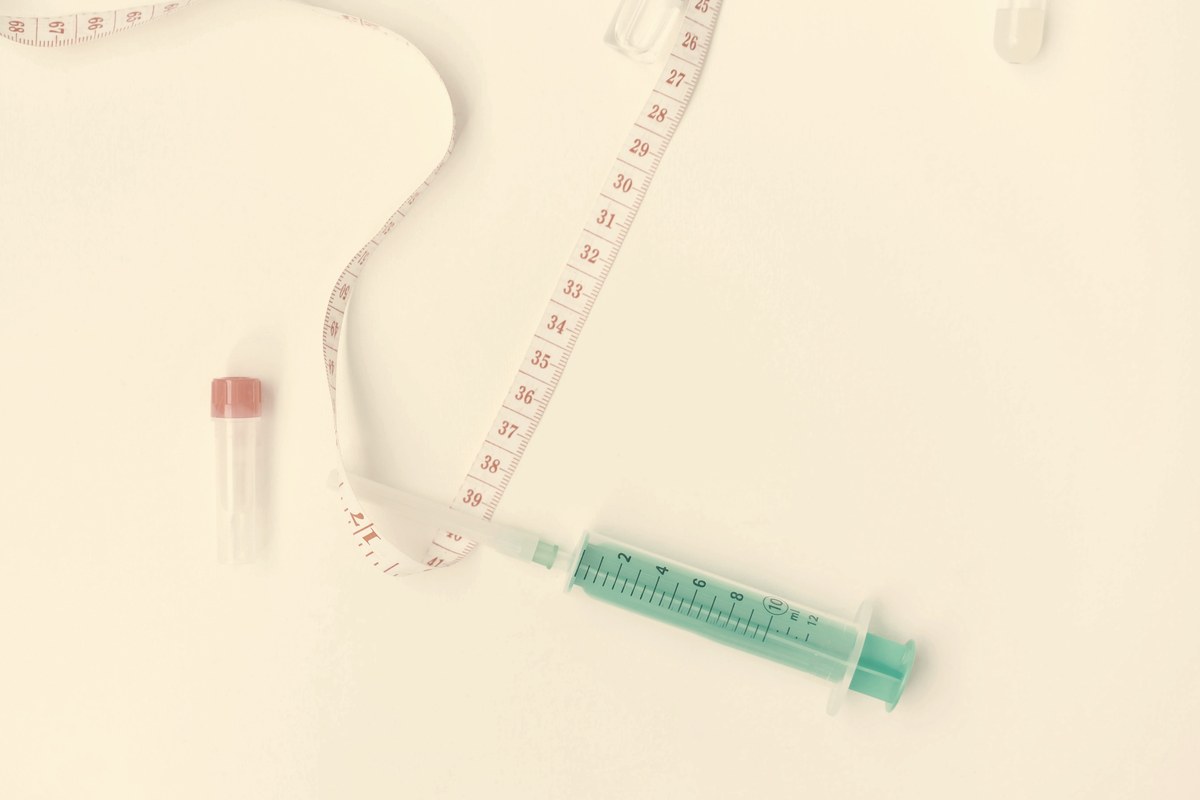 Syringe and tape measure on white background — representing tirzepatide microdose calculation